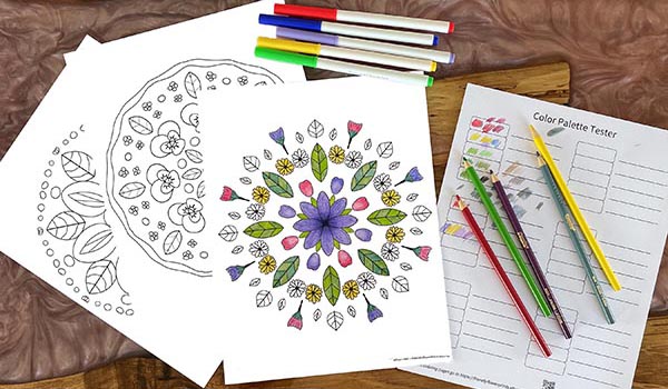 three coloring pages and a color palette tester with colored pencils and markers scattered around